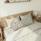 Bedroom with wooden bed frame, white bedding, and decorative pillows.