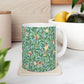 A ceramic mug with a blue background featuring a floral pattern of birds and pomegranates.