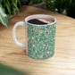 A ceramic mug with a blue background featuring a floral pattern of birds and pomegranates.