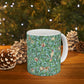 A ceramic mug with a blue background featuring a floral pattern of birds and pomegranates.