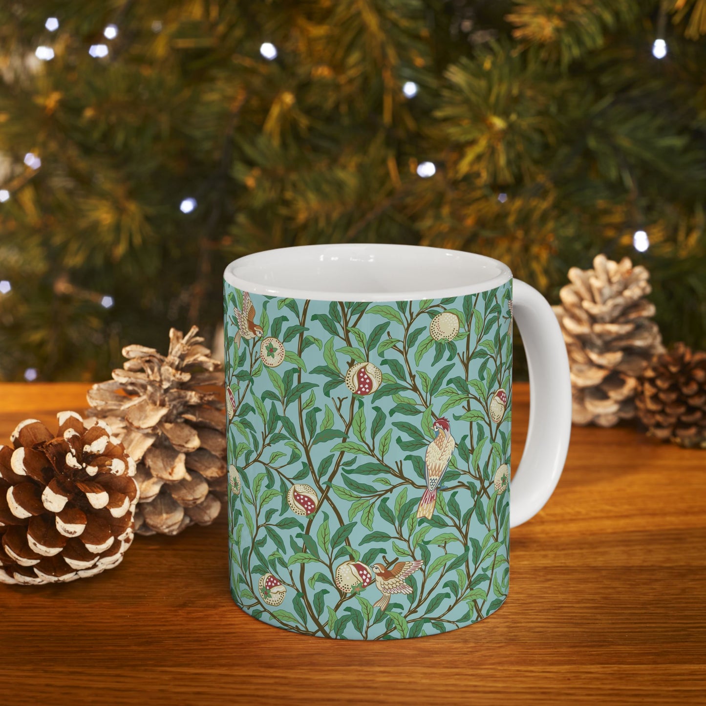 A ceramic mug with a blue background featuring a floral pattern of birds and pomegranates.