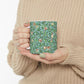 A ceramic mug with a blue background featuring a floral pattern of birds and pomegranates.