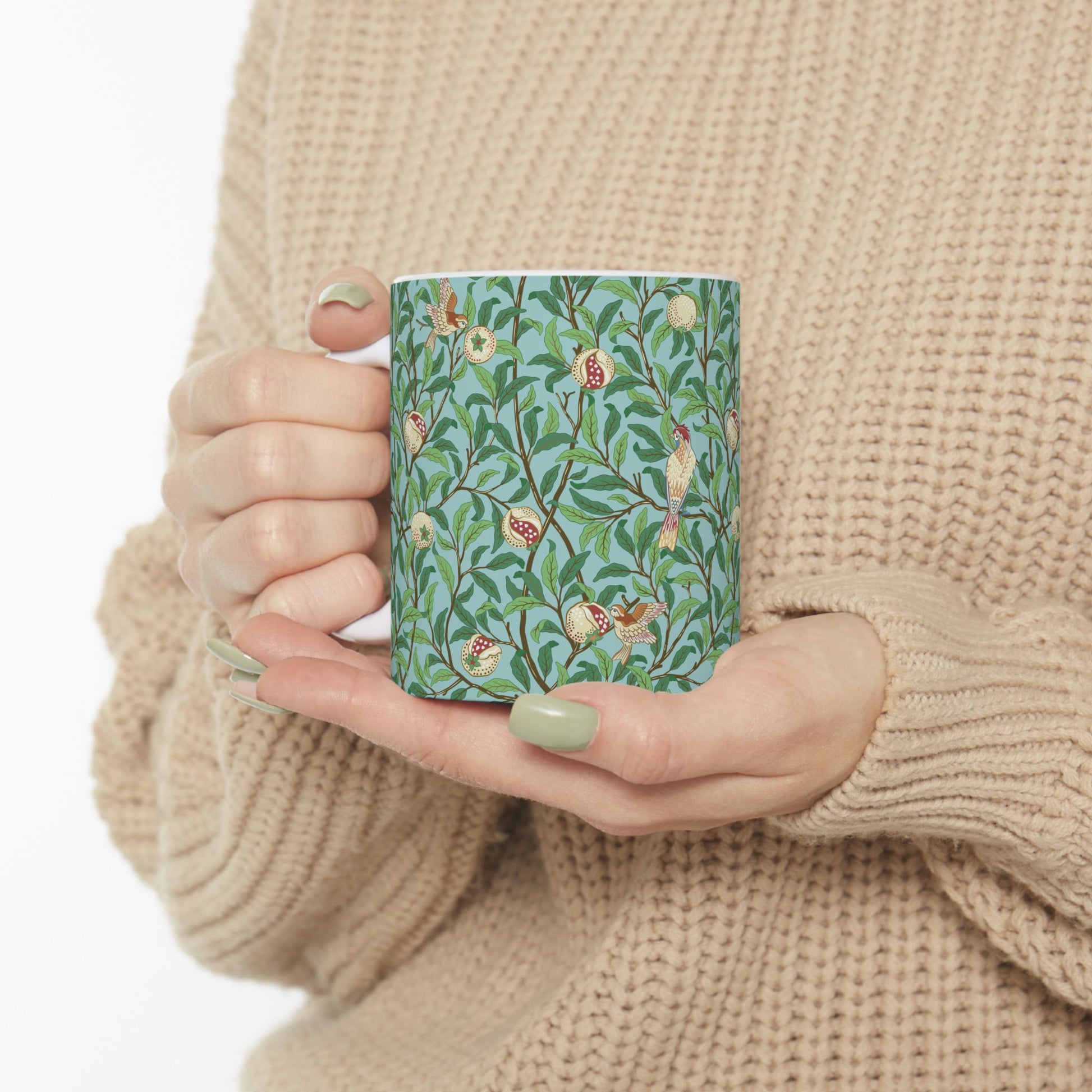 A ceramic mug with a blue background featuring a floral pattern of birds and pomegranates.