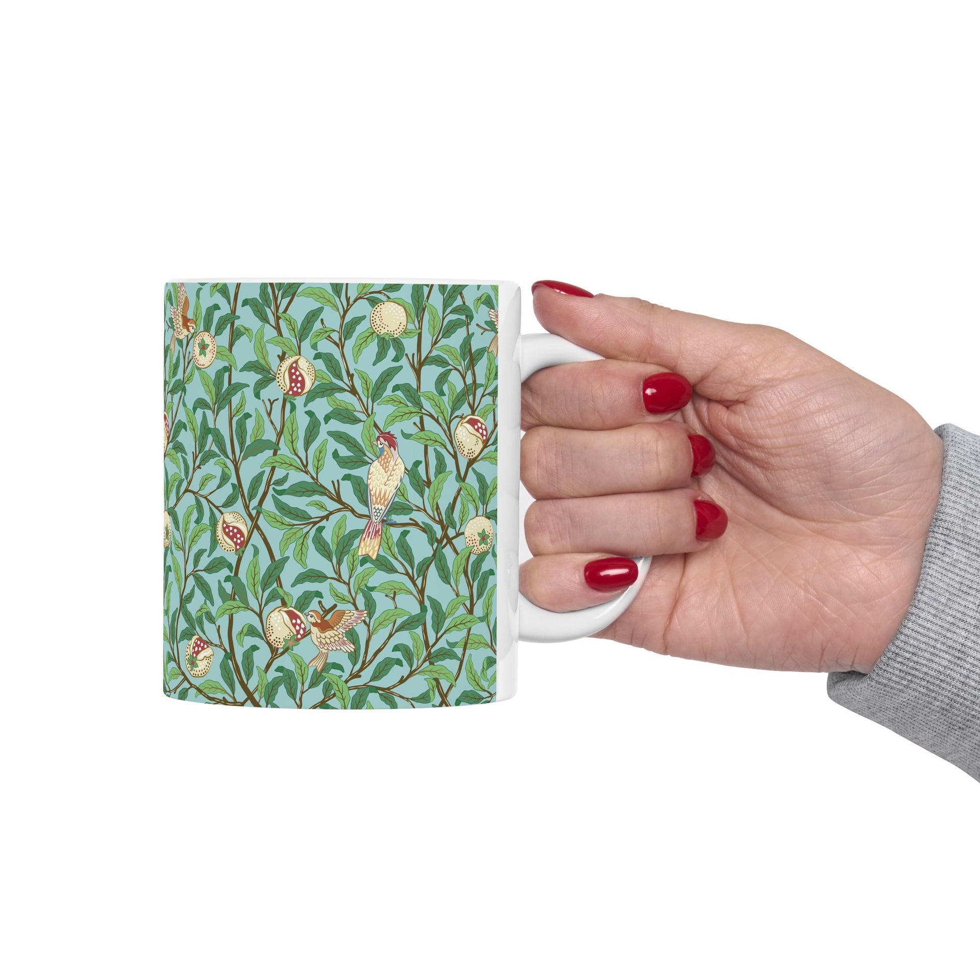 A ceramic mug with a blue background featuring a floral pattern of birds and pomegranates.