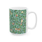 A ceramic mug with a blue background featuring a floral pattern of birds and pomegranates.