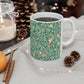 A ceramic mug with a blue background featuring a floral pattern of birds and pomegranates.