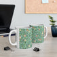 A ceramic mug with a blue background featuring a floral pattern of birds and pomegranates.