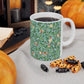 A ceramic mug with a blue background featuring a floral pattern of birds and pomegranates.