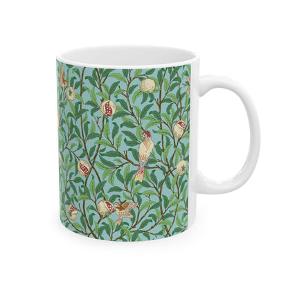 A ceramic mug with a blue background featuring a floral pattern of birds and pomegranates.