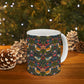 Mug with floral and bird pattern on a wooden surface with pinecones and a Christmas tree in the background.