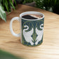 A ceramic mug with a design of two white swans on a green and blue background, inspired by the art of William Morris.