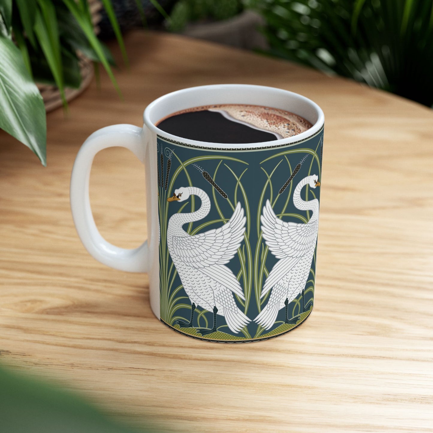 A ceramic mug with a design of two white swans on a green and blue background, inspired by the art of William Morris.