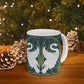 A ceramic mug with a design of two white swans on a green and blue background, inspired by the art of William Morris.