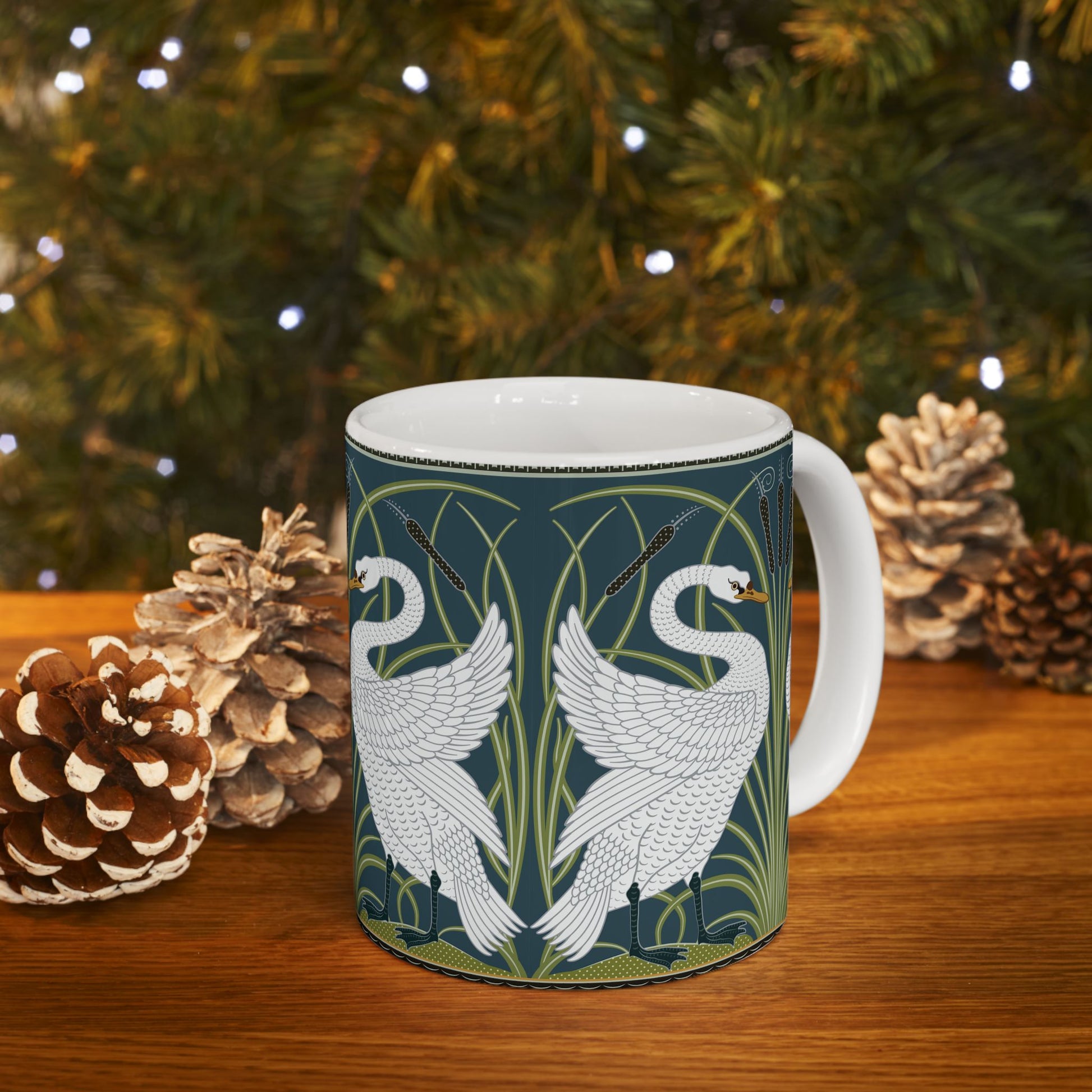 A ceramic mug with a design of two white swans on a green and blue background, inspired by the art of William Morris.