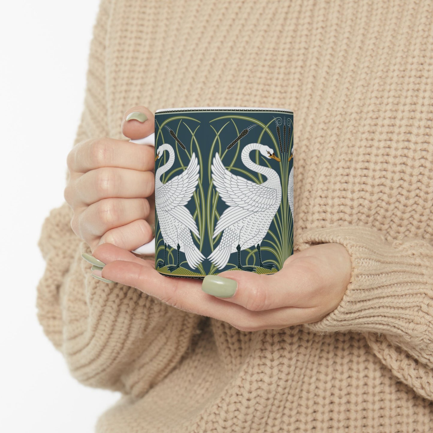 A ceramic mug with a design of two white swans on a green and blue background, inspired by the art of William Morris.