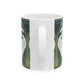 A ceramic mug with a design of two white swans on a green and blue background, inspired by the art of William Morris.