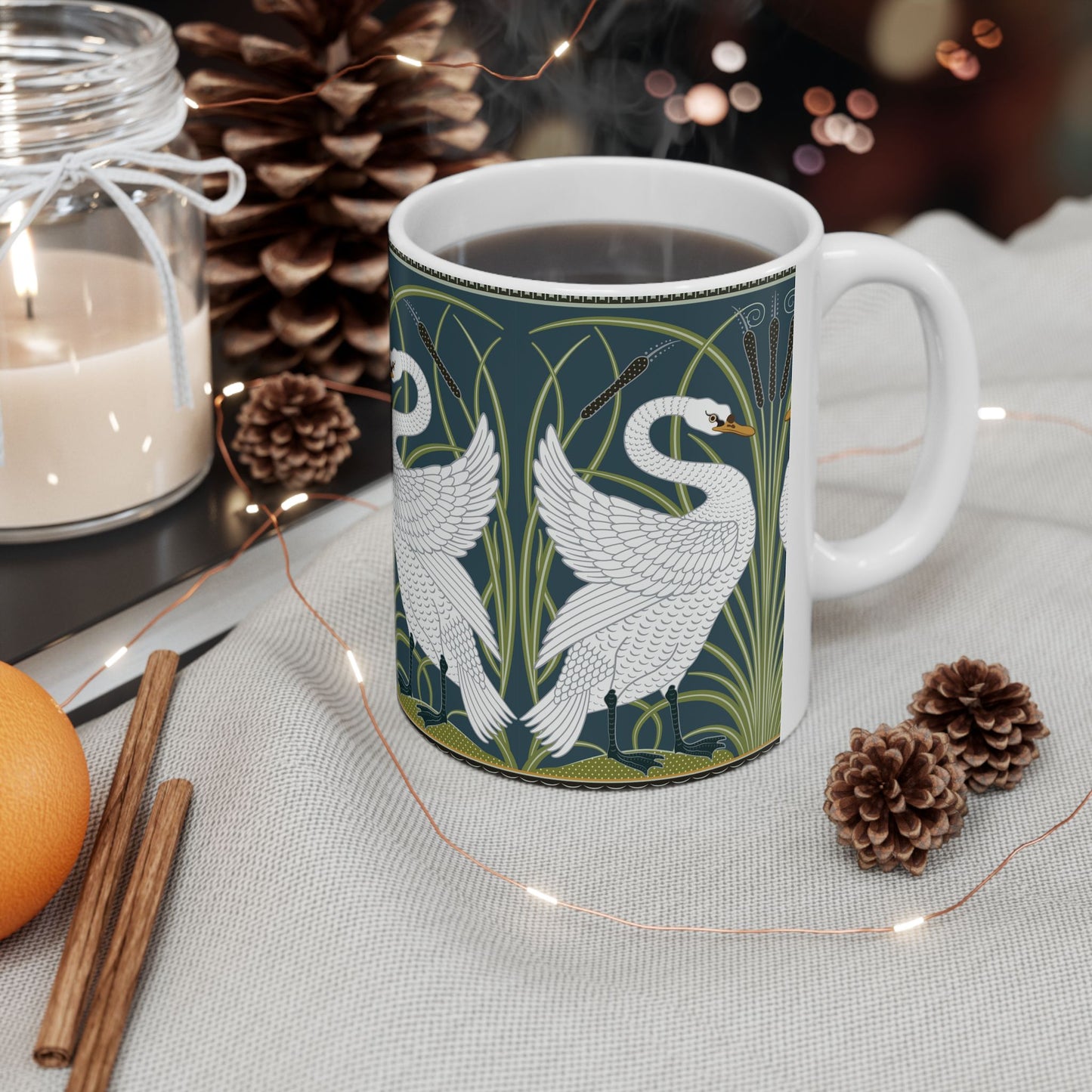 A ceramic mug with a design of two white swans on a green and blue background, inspired by the art of William Morris.