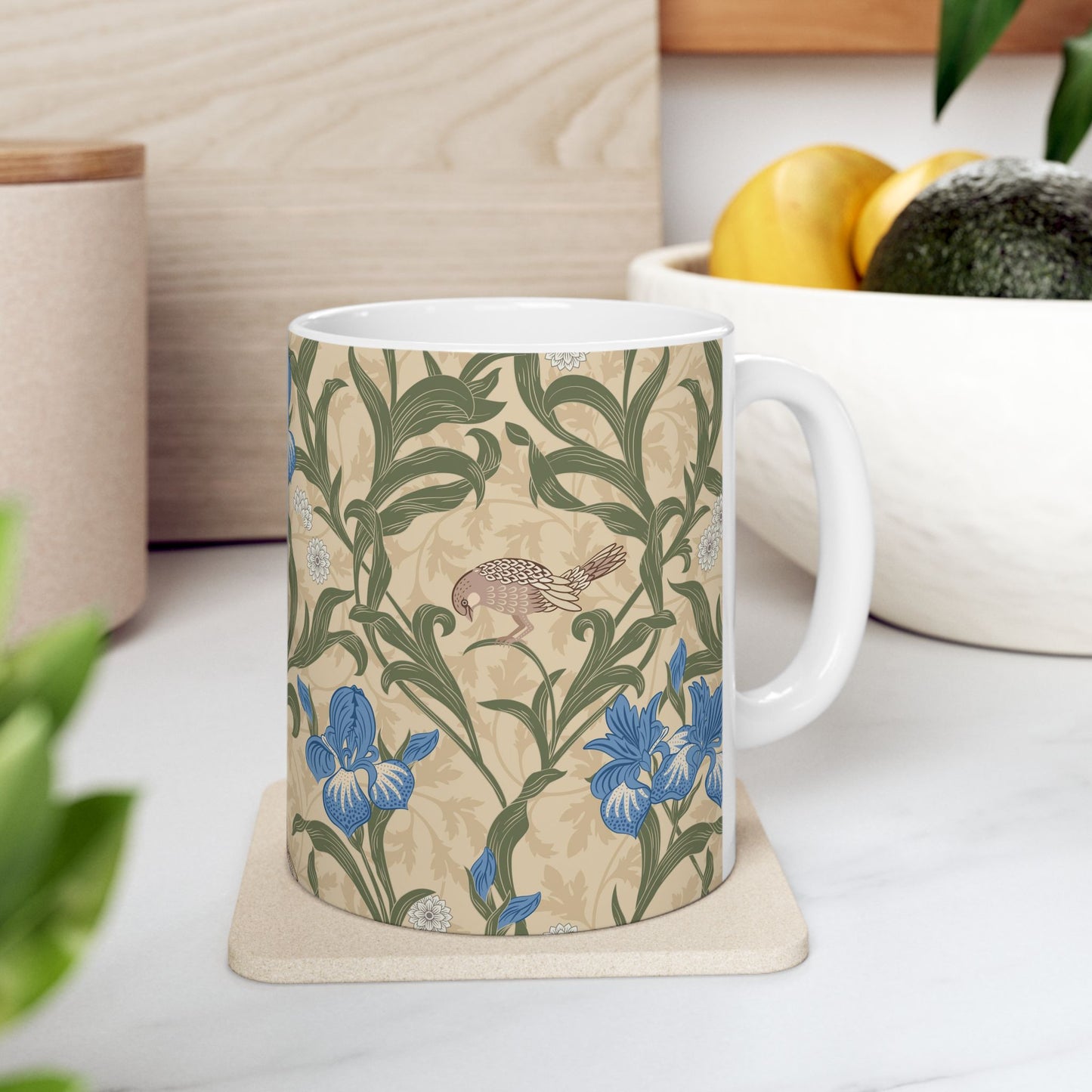 A ceramic mug with a floral William Morris & Co pattern design, featuring a bird and various flowers in shades of blue, green and beige.