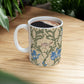 A ceramic mug with a floral William Morris & Co pattern design, featuring a bird and various flowers in shades of blue, green and beige.