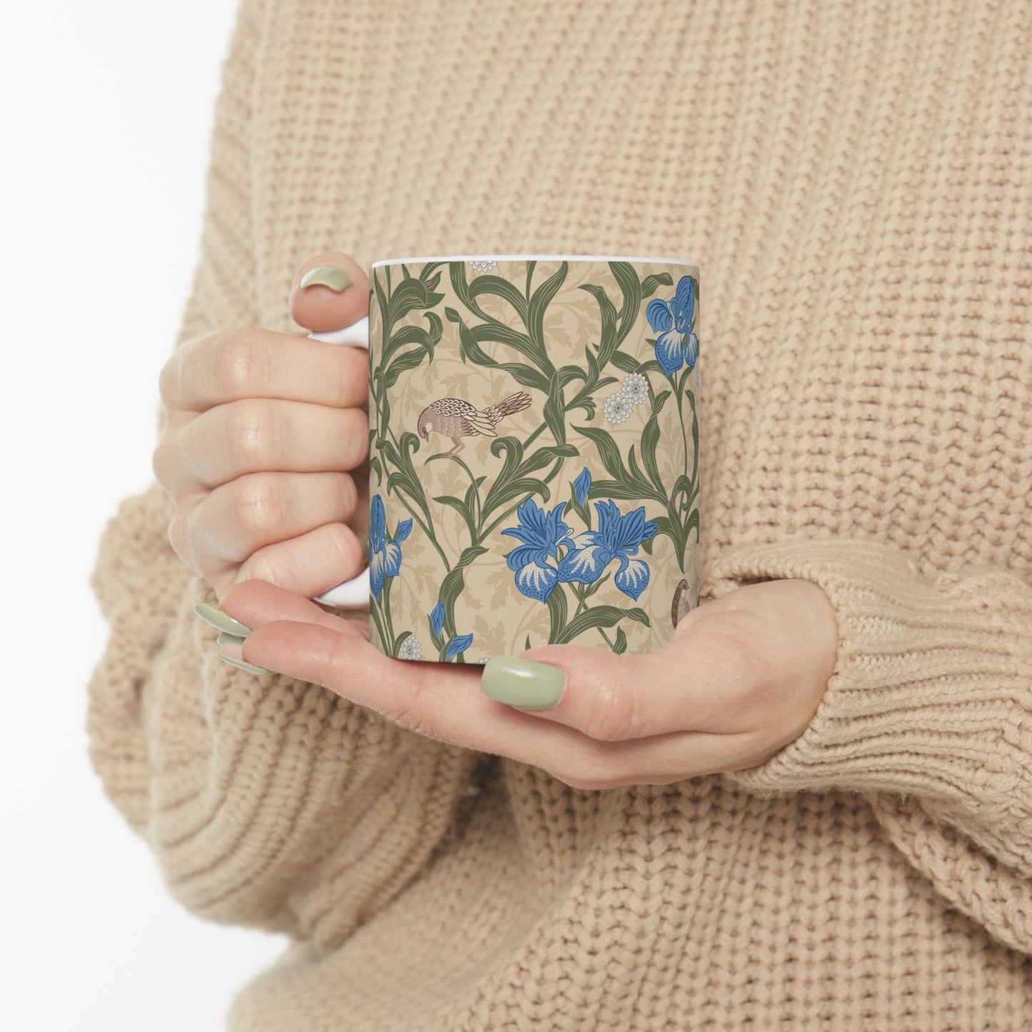 A ceramic mug with a floral William Morris & Co pattern design, featuring a bird and various flowers in shades of blue, green and beige.