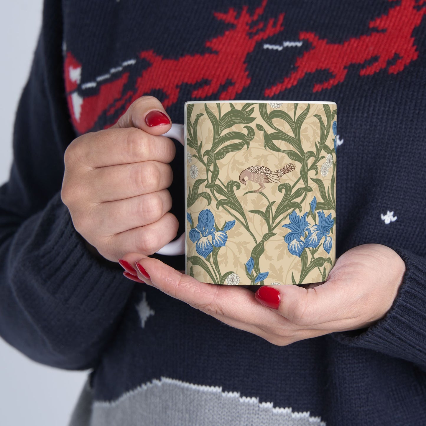 A ceramic mug with a floral William Morris & Co pattern design, featuring a bird and various flowers in shades of blue, green and beige.
