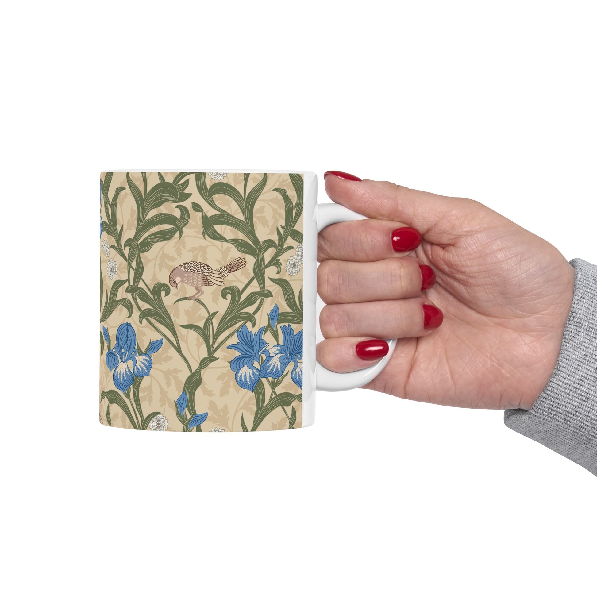 A ceramic mug with a floral William Morris & Co pattern design, featuring a bird and various flowers in shades of blue, green and beige.