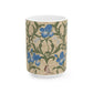 A ceramic mug with a floral William Morris & Co pattern design, featuring a bird and various flowers in shades of blue, green and beige.