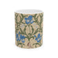 A ceramic mug with a floral William Morris & Co pattern design, featuring a bird and various flowers in shades of blue, green and beige.