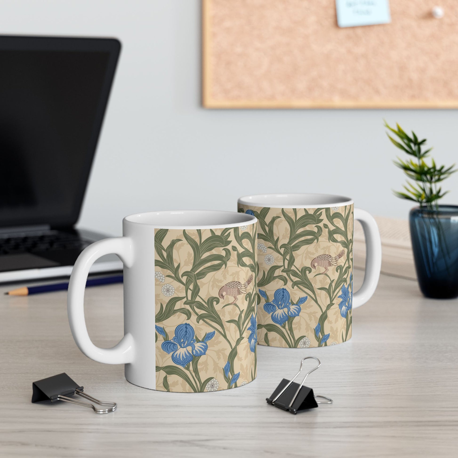A ceramic mug with a floral William Morris & Co pattern design, featuring a bird and various flowers in shades of blue, green and beige.
