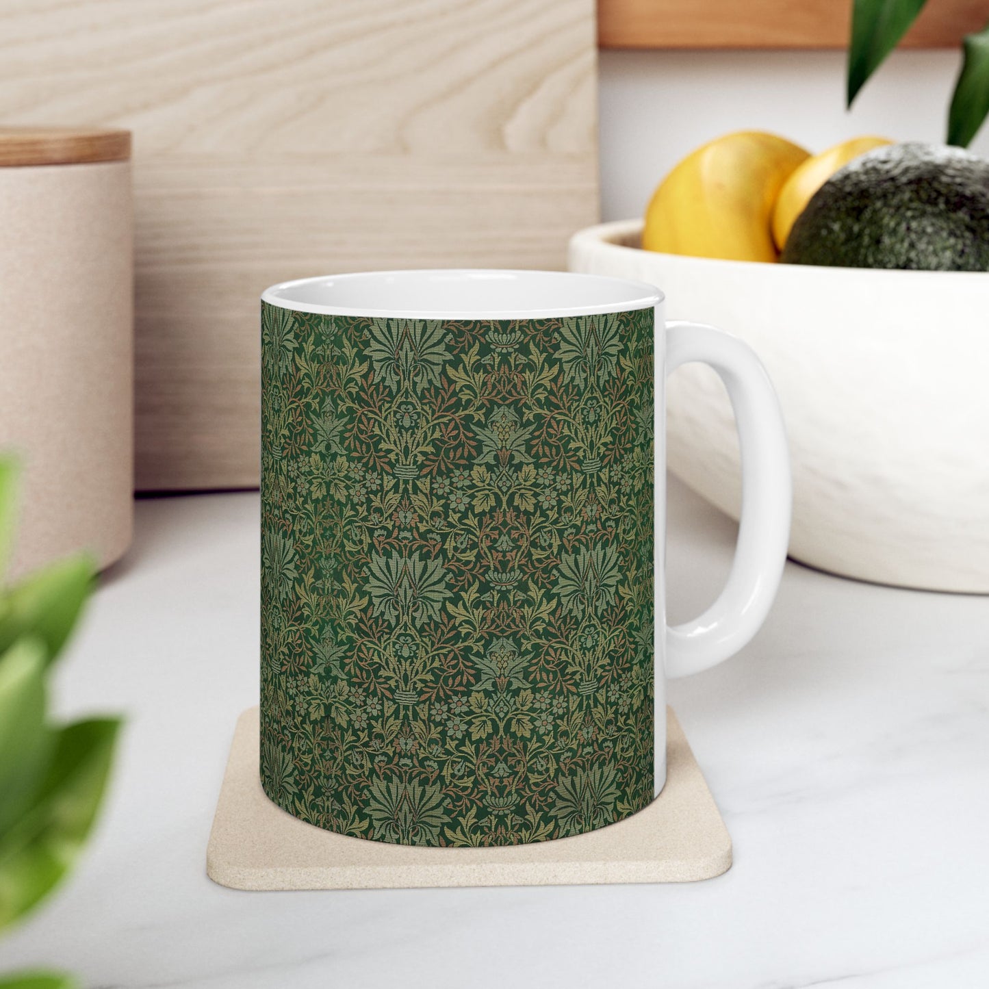 A ceramic mug with a floral garden William Morris & Co pattern design, predominantly green and white.
