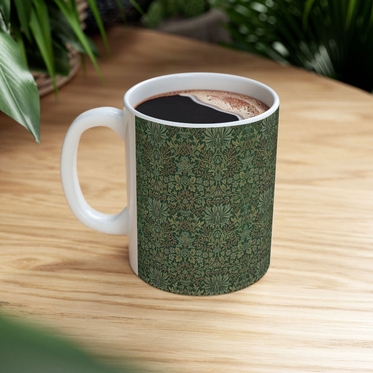 A ceramic mug with a floral garden William Morris & Co pattern design, predominantly green and white.