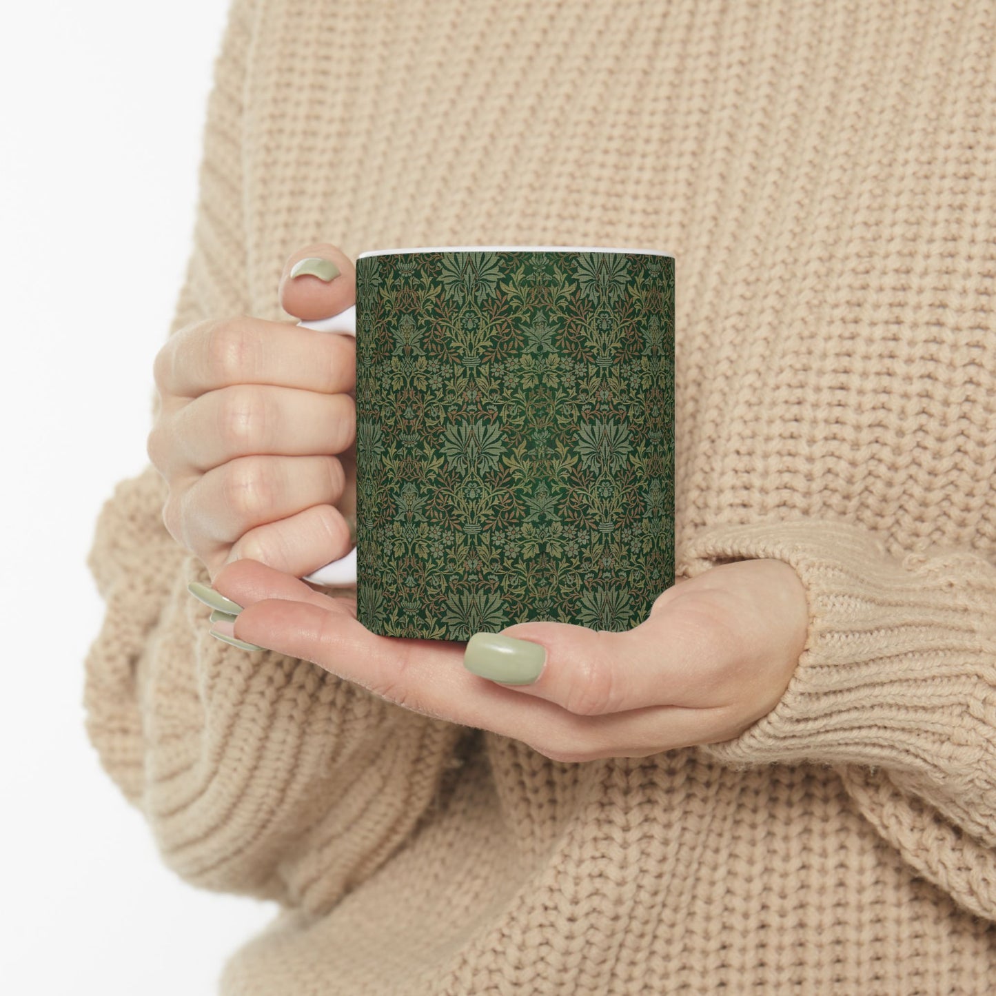A ceramic mug with a floral garden William Morris & Co pattern design, predominantly green and white.