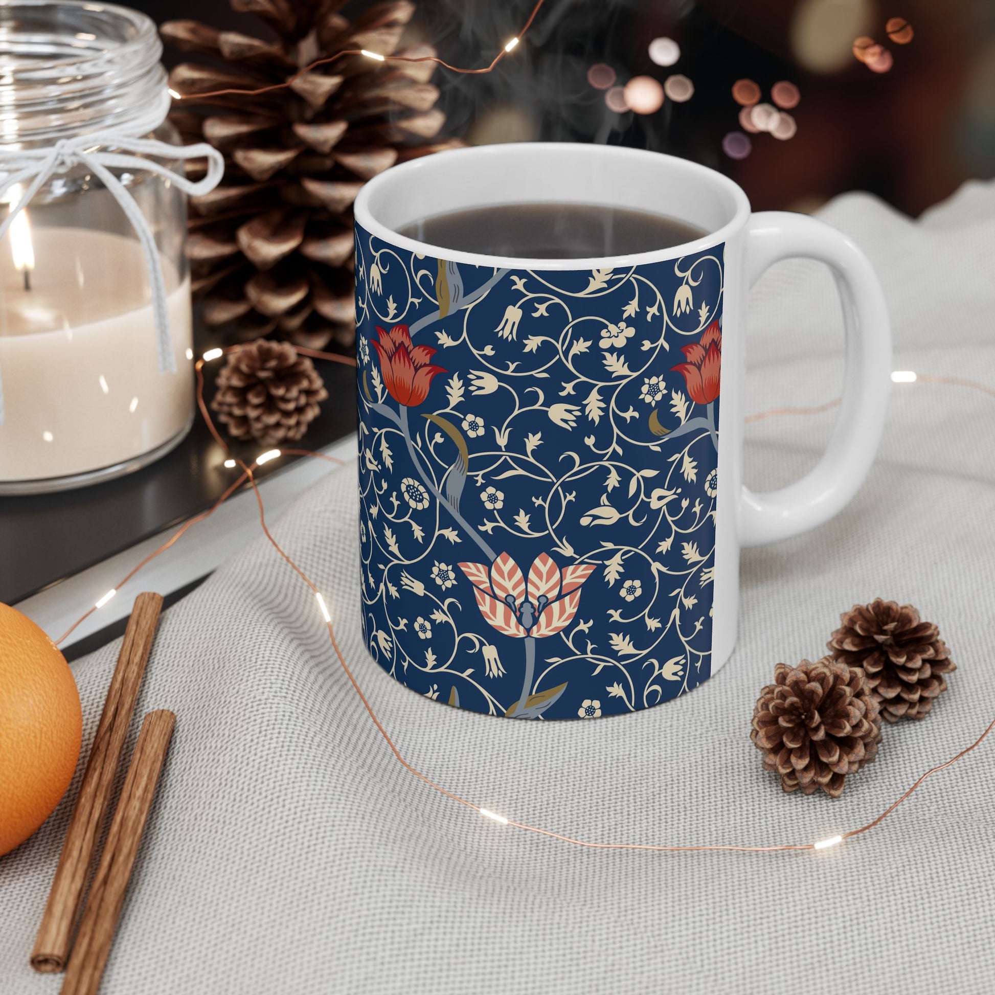 A ceramic mug with a floral pattern and a white handle featuring a blue. white, red and pink pattern design called Medway by William Morris & Co