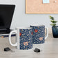 A ceramic mug with a floral pattern and a white handle featuring a blue. white, red and pink pattern design called Medway by William Morris & Co