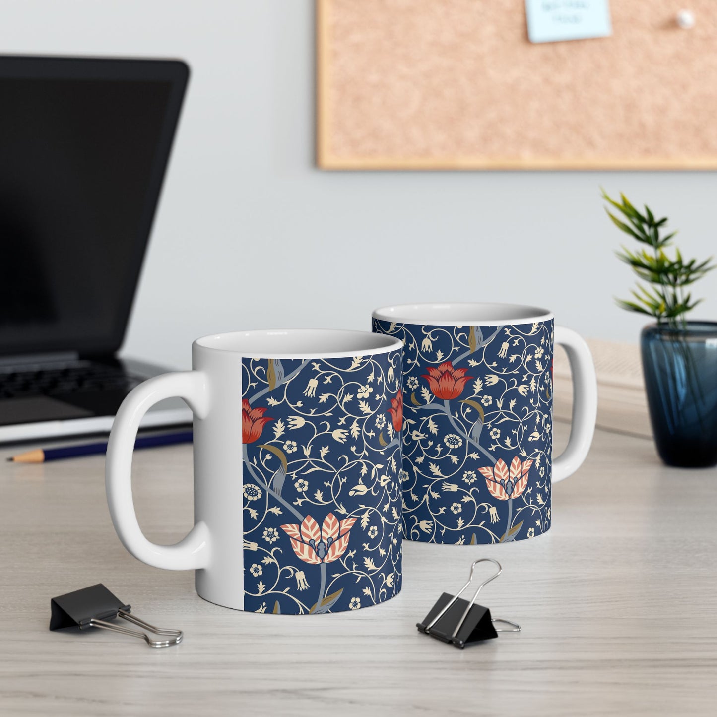 A ceramic mug with a floral pattern and a white handle featuring a blue. white, red and pink pattern design called Medway by William Morris & Co