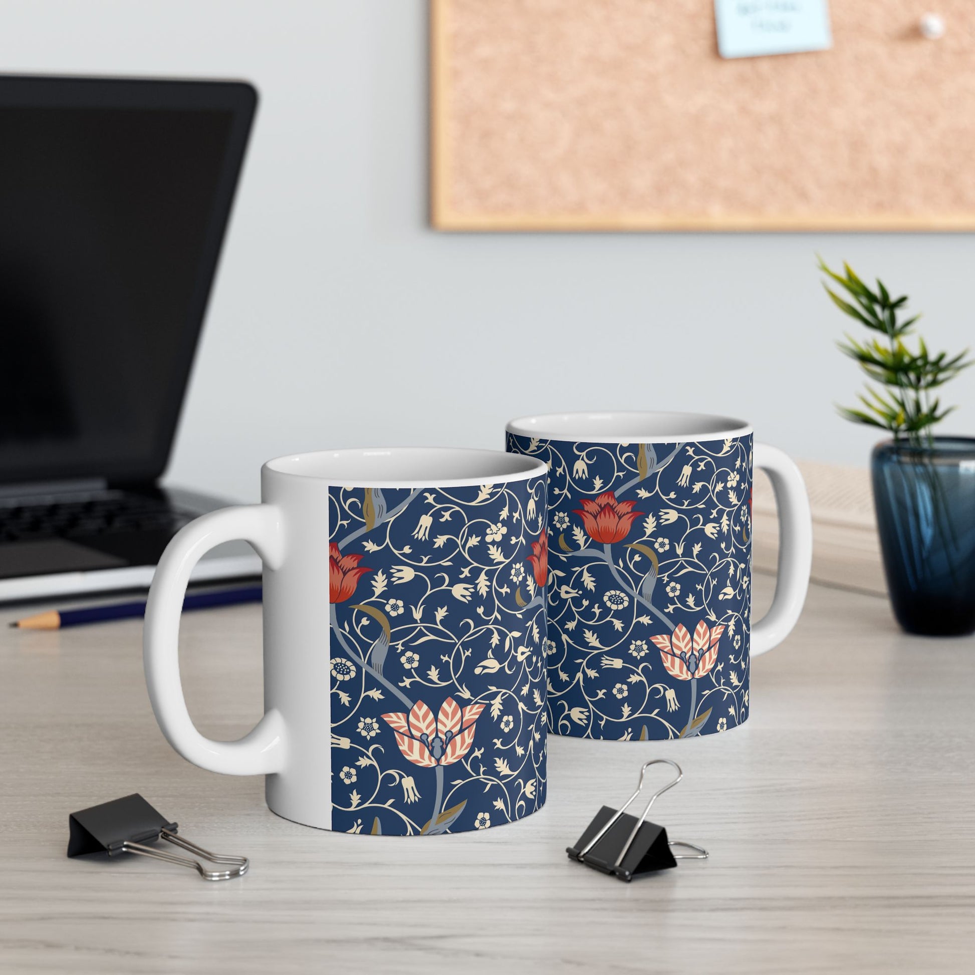 A ceramic mug with a floral pattern and a white handle featuring a blue. white, red and pink pattern design called Medway by William Morris & Co