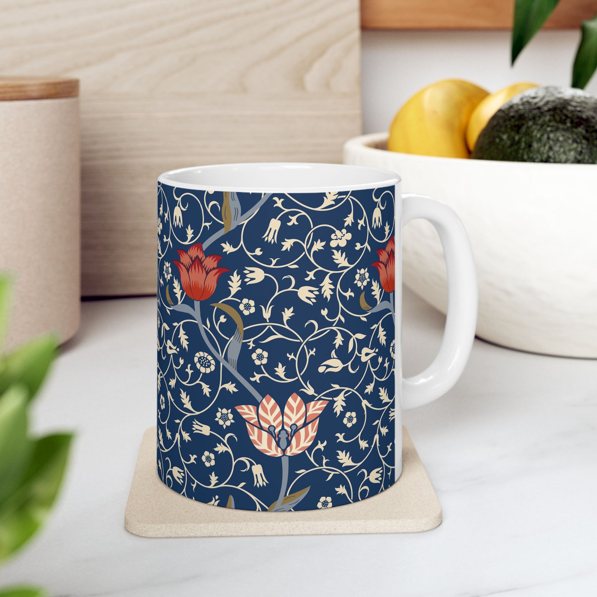 A ceramic mug with a floral pattern and a white handle featuring a blue. white, red and pink pattern design called Medway by William Morris & Co