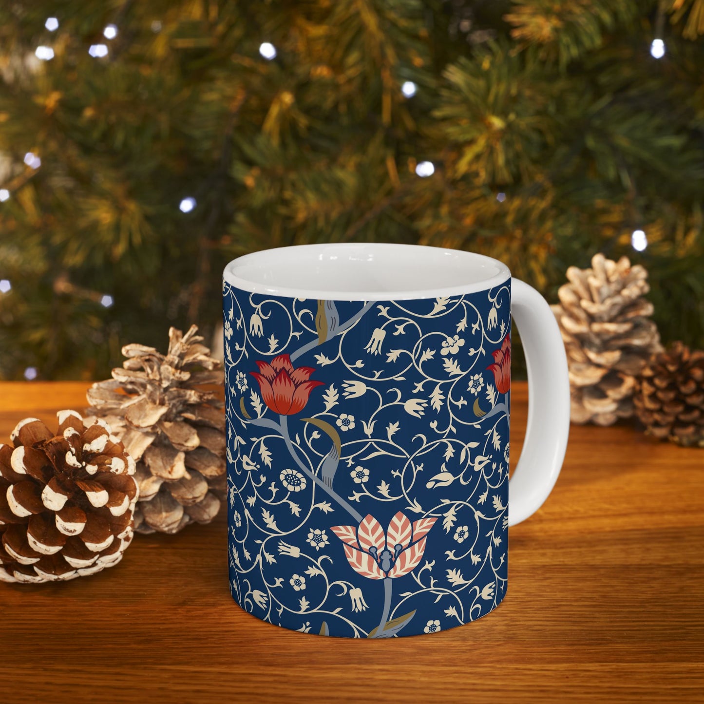 A ceramic mug with a floral pattern and a white handle featuring a blue. white, red and pink pattern design called Medway by William Morris & Co