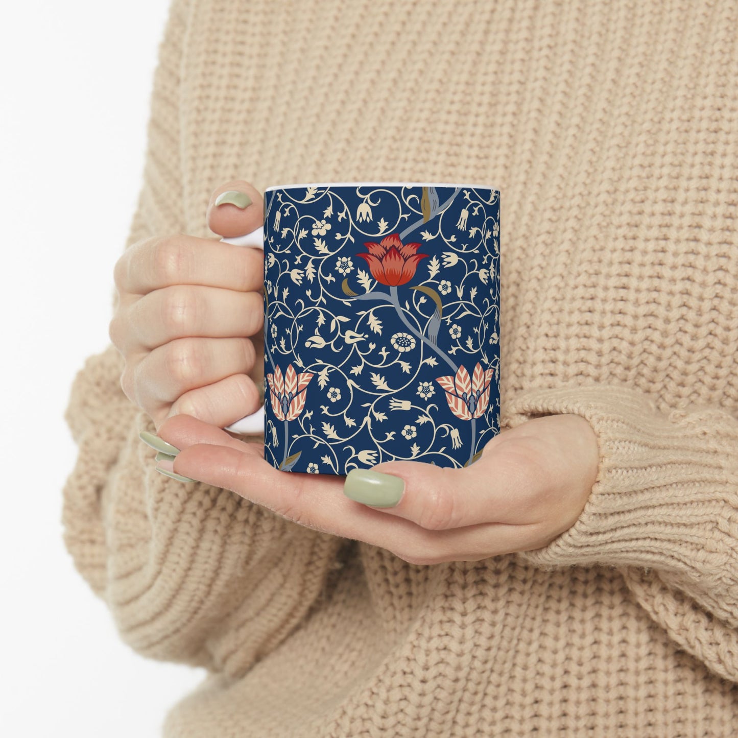 A ceramic mug with a floral pattern and a white handle featuring a blue. white, red and pink pattern design called Medway by William Morris & Co
