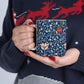 A ceramic mug with a floral pattern and a white handle featuring a blue. white, red and pink pattern design called Medway by William Morris & Co