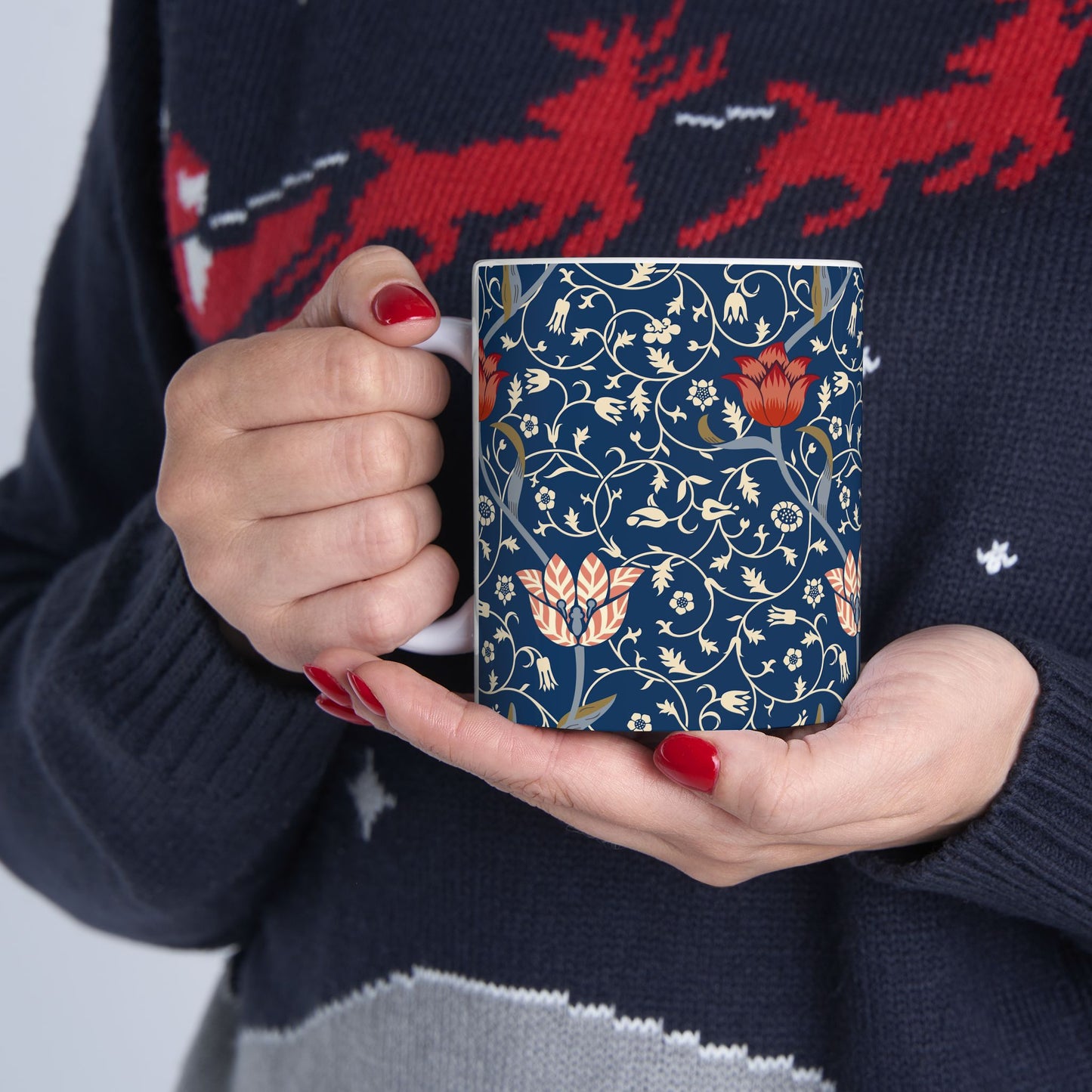 A ceramic mug with a floral pattern and a white handle featuring a blue. white, red and pink pattern design called Medway by William Morris & Co
