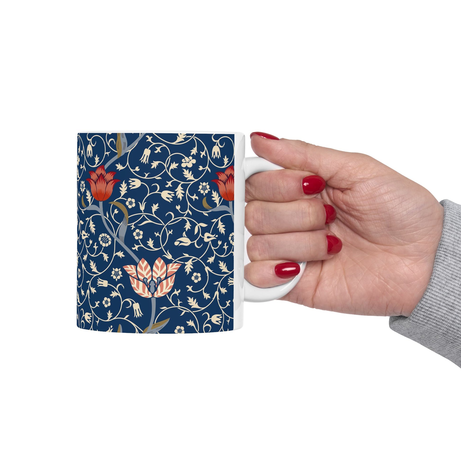 A ceramic mug with a floral pattern and a white handle featuring a blue. white, red and pink pattern design called Medway by William Morris & Co