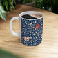 A ceramic mug with a floral pattern and a white handle featuring a blue. white, red and pink pattern design called Medway by William Morris & Co