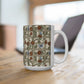 A white ceramic mug with a vintage-style floral trellis pattern, sitting on a wooden table with a blurred laptop in the background.