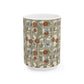 A white ceramic mug featuring a vintage-style floral trellis pattern with red-orange flowers, blue butterflies, and green leaves on a beige background.