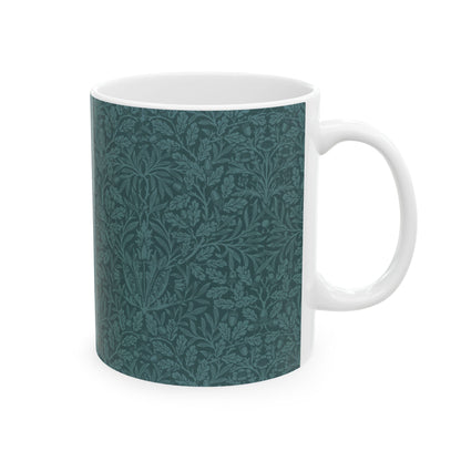 A ceramic mug with a teal base and a white handle featuring a floral and acorn pattern design, inspired by William Morris.