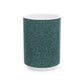 A ceramic mug with a teal base and a white handle featuring a floral and acorn pattern design, inspired by William Morris.