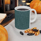A ceramic mug with a teal base and a white handle featuring a floral and acorn pattern design, inspired by William Morris.