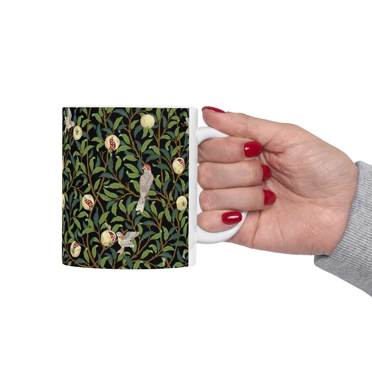 A ceramic mug with a black background featuring a floral William Morris & Co pattern of birds and pomegranates.
