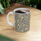 A white ceramic mug with a pink floral and pomegranate design inspired by William Morris.